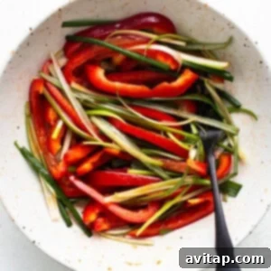 A bowl of sliced red bell peppers and green onions ready for cooking with Korean ground beef, accompanied by a spoon.