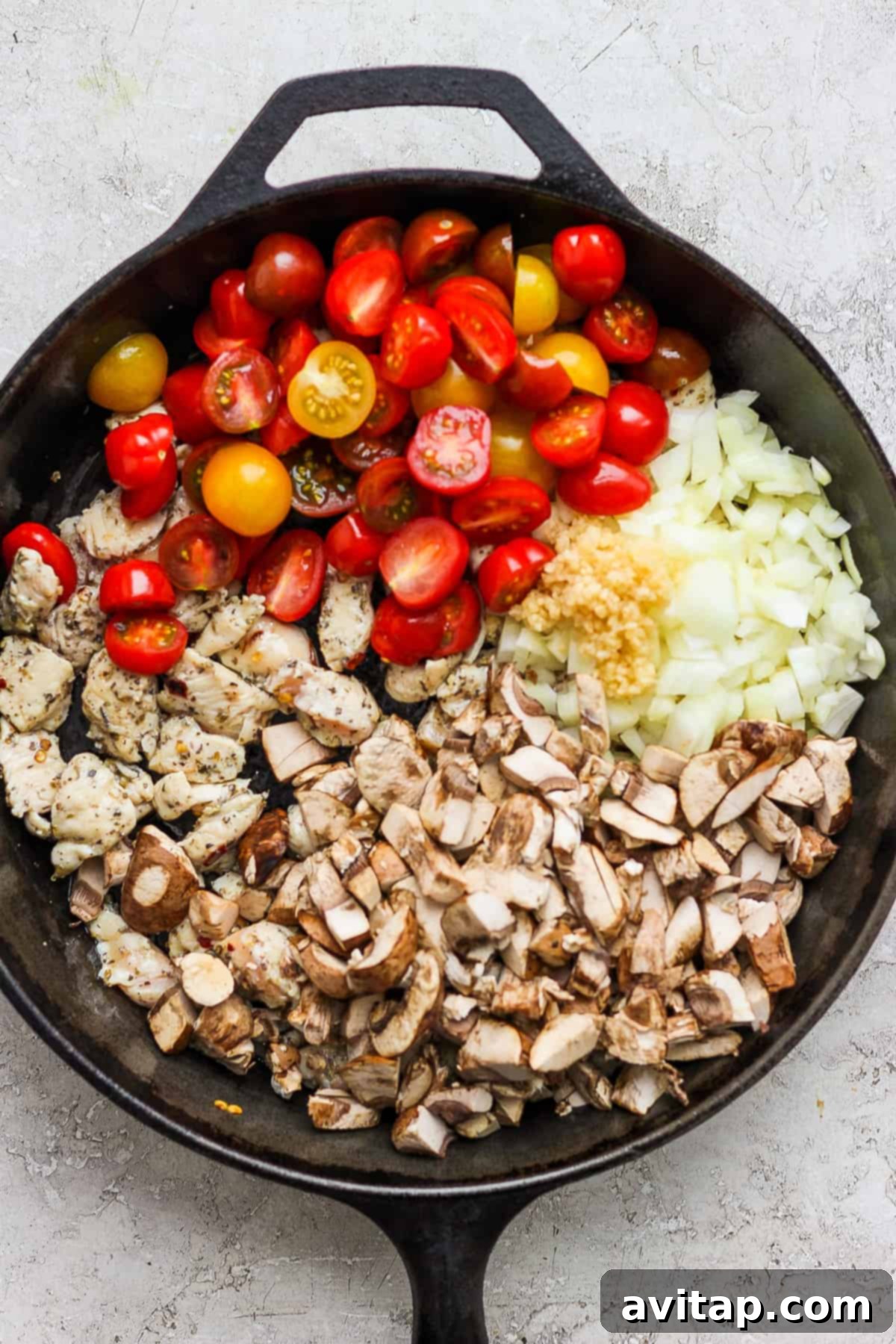 A frying pan with tomatoes, onions, and mushrooms beginning to cook, setting the stage for the one-pot meal.
