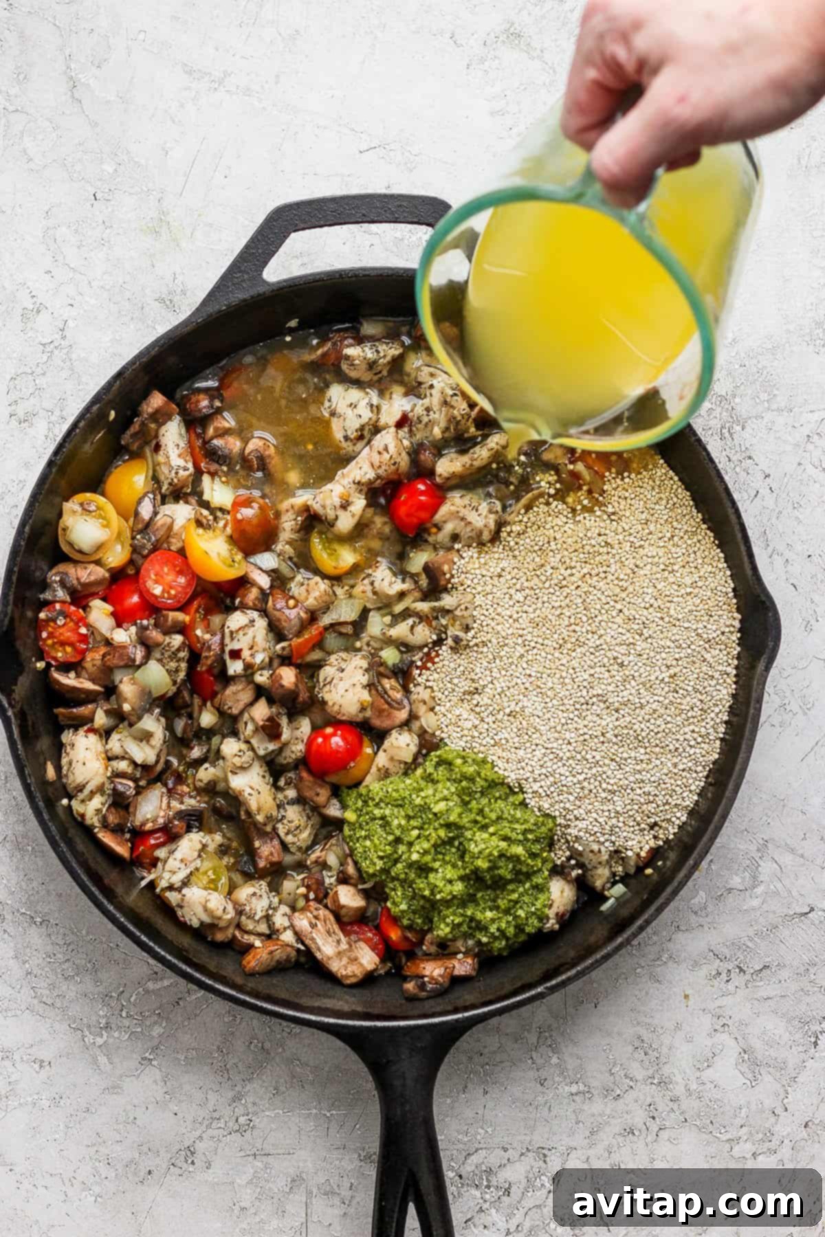 A person pouring olive oil into a skillet, ready to begin cooking the chicken and vegetables for the pesto chicken quinoa skillet.