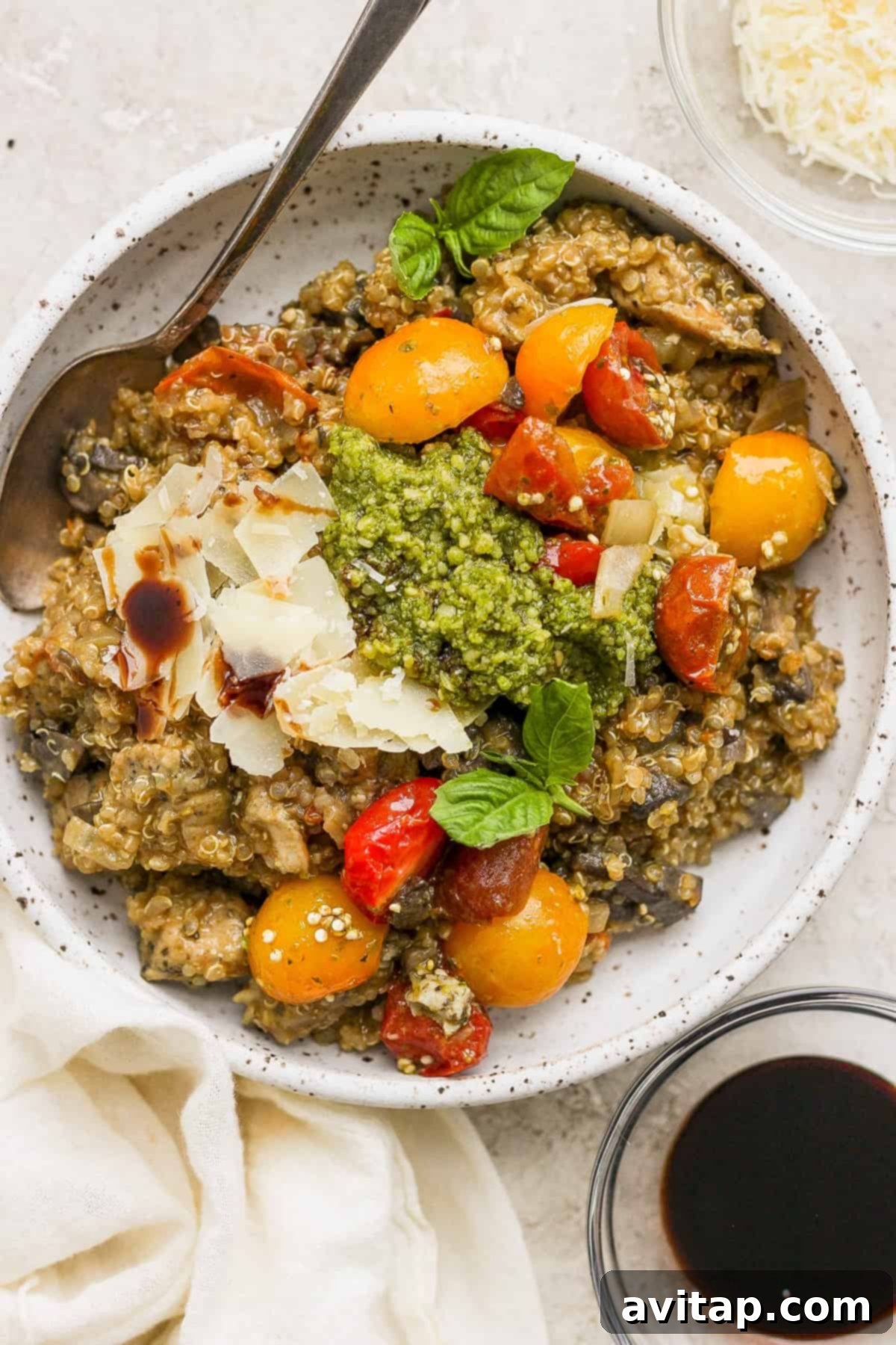 A bowl of pasta with tomatoes and pesto, representing a serving of the delicious pesto chicken quinoa skillet.