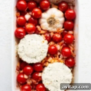 A white baking dish filled with vibrant cherry tomatoes, a block of Boursin cheese, and fragrant herbs, glistening with olive oil.