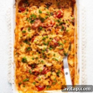 A casserole dish with a fork mashing roasted tomatoes and garlic, preparing the creamy Boursin sauce.
