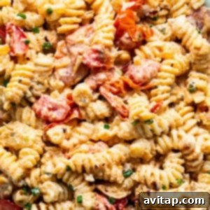 A bowl of creamy pasta salad with cooked shrimp and colorful diced vegetables, tossed in a rich Boursin sauce.