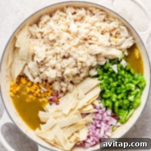 Mexican chicken enchiladas in a pan with corn and peas, mixture before broiling.