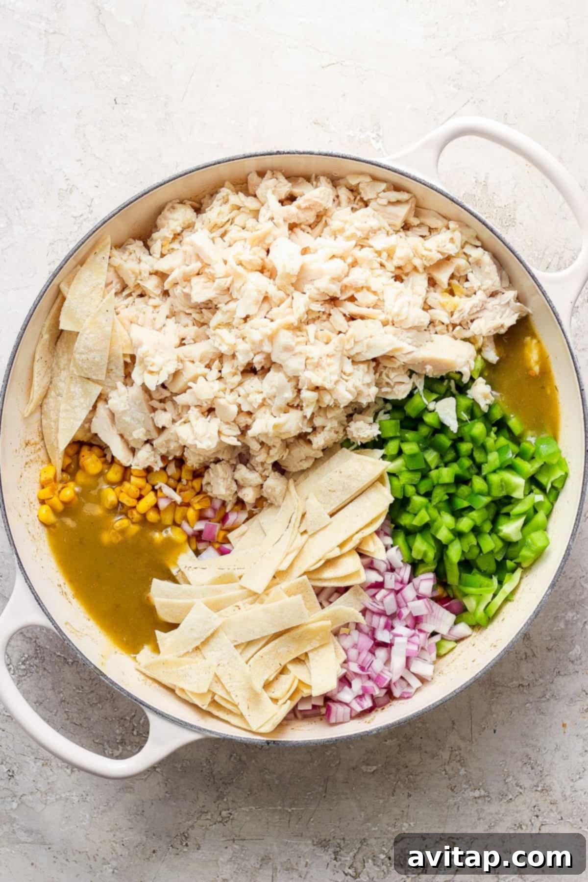 Mexican chicken enchiladas in a pan with corn and peas, ready to be broiled.