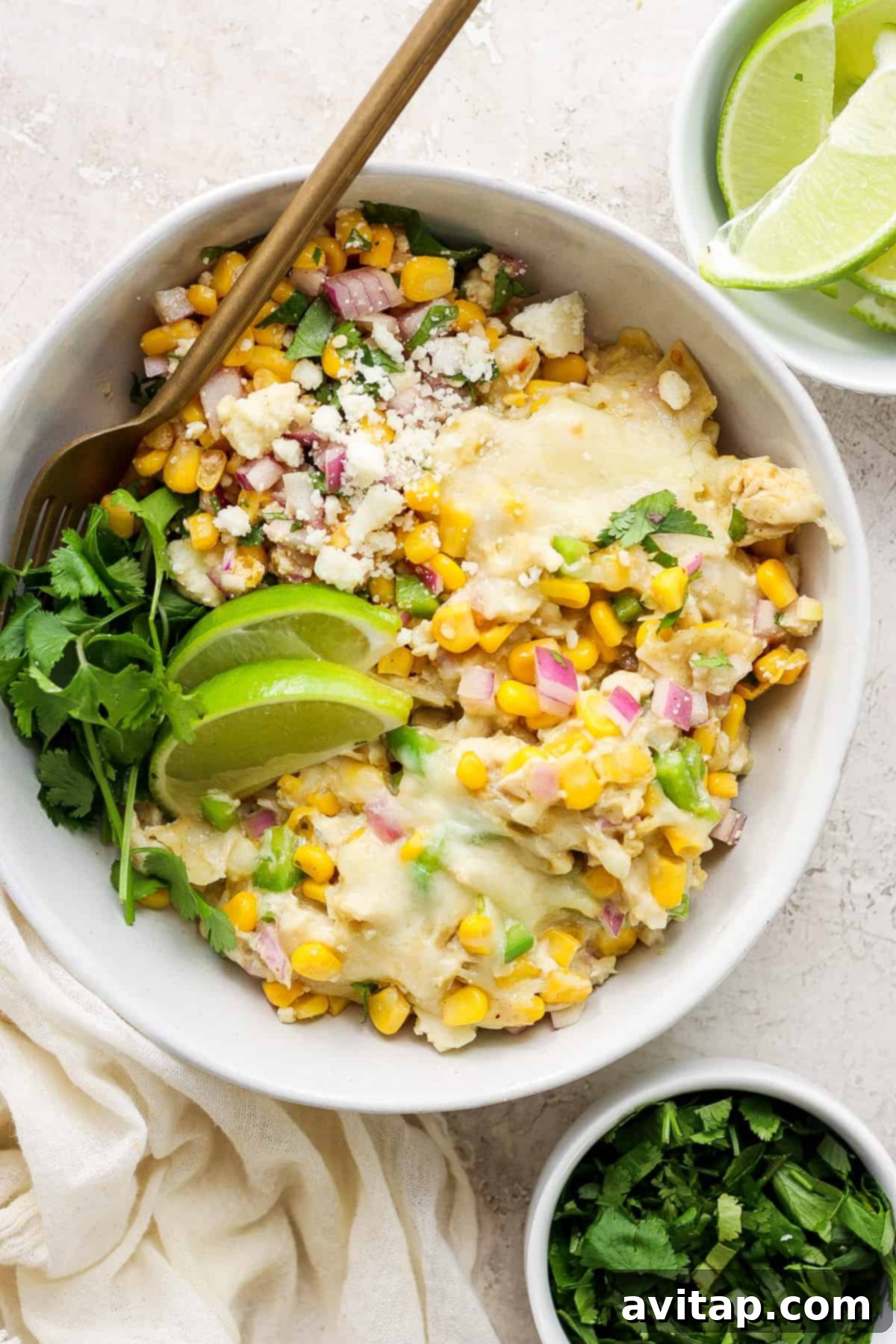 Mexican chicken and corn enchiladas in a white bowl, garnished with fresh cilantro.