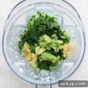 All fresh herbs, avocado, and spices being blended into the dressing to create a rich, creamy, and vibrantly green mixture.