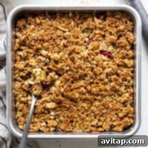 A baking dish filled with golden-brown rhubarb crisp, fresh from the oven, with fruit bubbling at the edges.