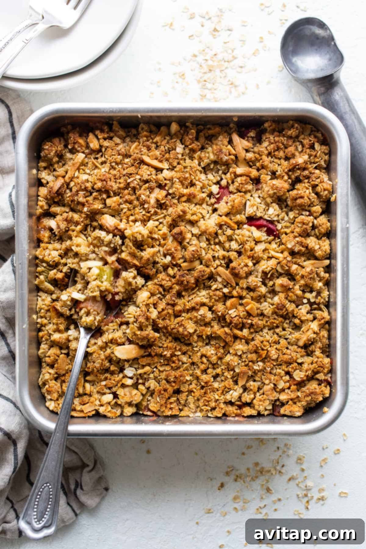 A golden-brown rhubarb crisp fresh out of the oven, bubbling along the edges in a clear baking dish.