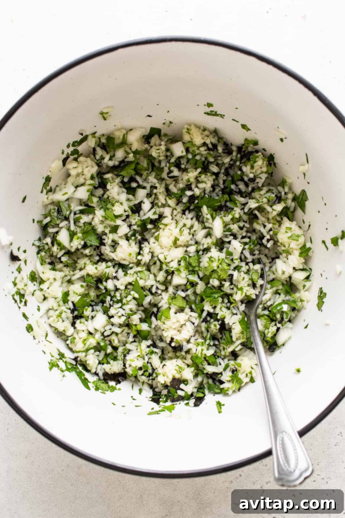 A white bowl brimming with fresh, colorful ingredients, including greens and a spoon, illustrating healthy and customizable options.