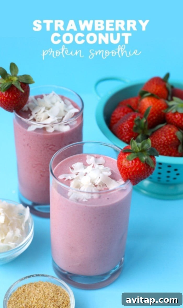 Strawberry Coconut Workout Refuel 2 Two vibrant strawberry coconut protein smoothies presented elegantly alongside bowls of fresh strawberries, shredded coconut, and other raw ingredients, highlighting their natural and appealing composition.