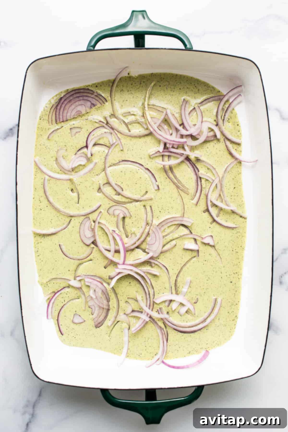 Fresh Prep Taco Bowl 3 A ceramic dish holding a vibrant creamy dressing, topped with thinly sliced red onions and fresh cilantro, ready to be layered into the salad.