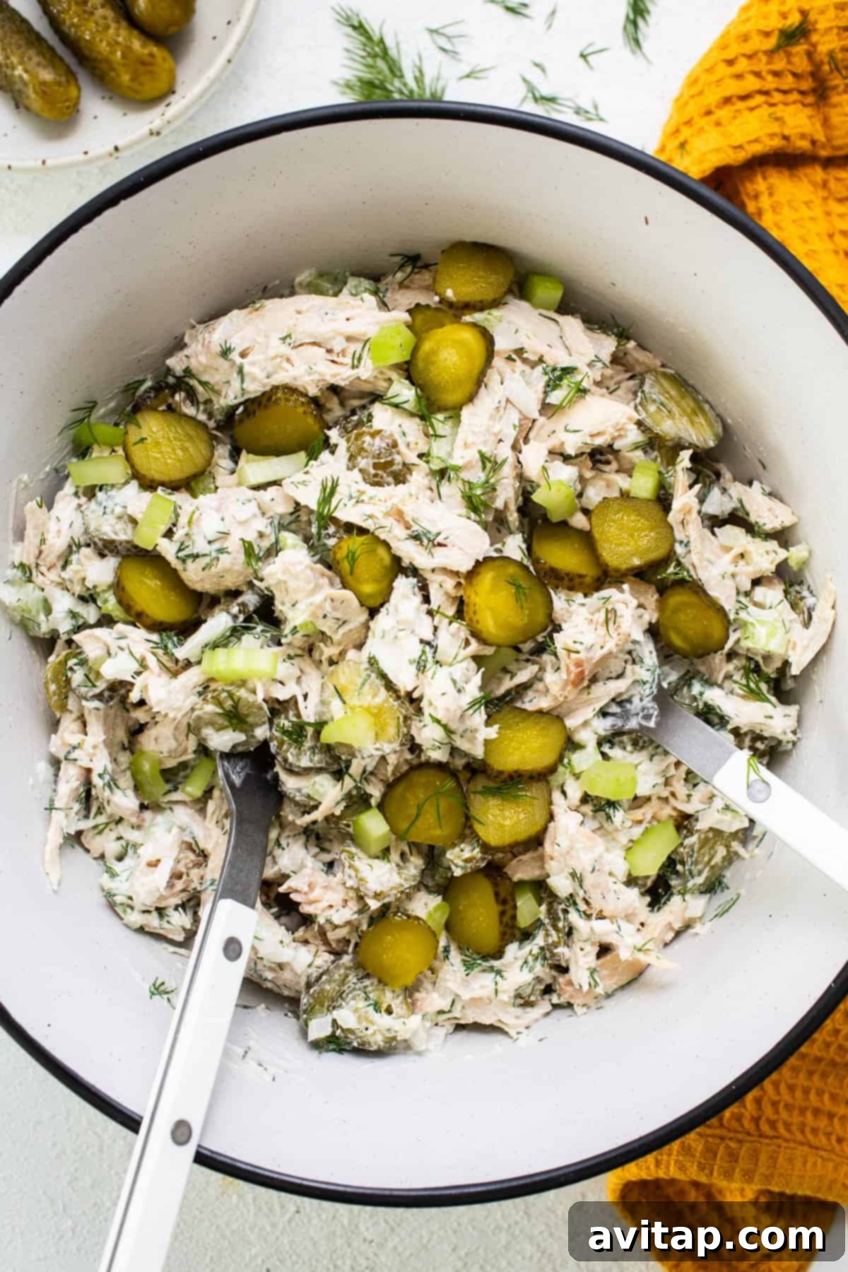 Tangy Dill Pickle Chicken Salad 5 A serving bowl filled with creamy dill pickle chicken salad, garnished with additional pickle slices and fresh dill sprigs, ready to be served.