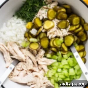 Tangy Dill Pickle Chicken Salad 8 Ingredients for a recipe including shredded chicken, chopped onions, sliced pickles, and diced celery in a bowl with tongs, ready for the dressing.