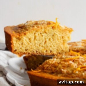 A sliced citrus-flavored pound cake with orange zest garnish on a white plate, highlighting its delicious texture.