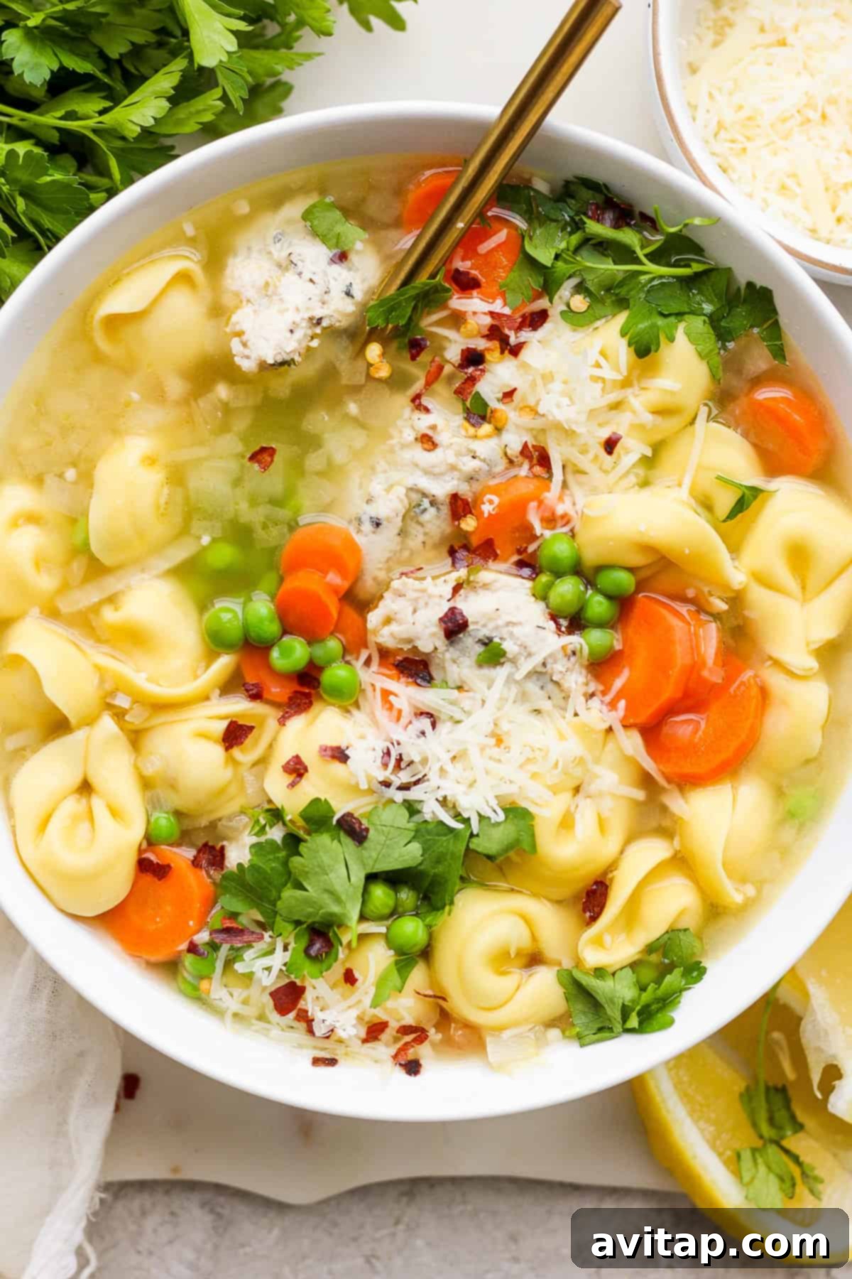 A cozy bowl of chicken noodle soup with vibrant vegetables, generously topped with grated Parmesan cheese and fresh herbs.