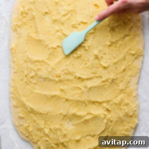 Almond filling spread on dough, being rolled into a log.