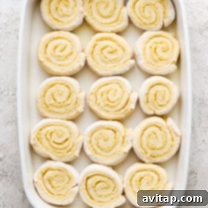 Dough log being sliced into individual cinnamon rolls.