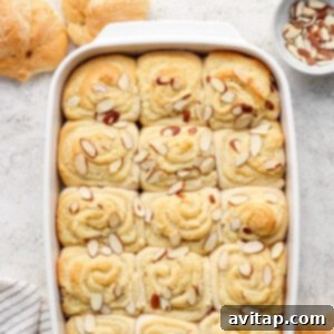 Freshly baked almond-topped sweet rolls in a white baking dish.