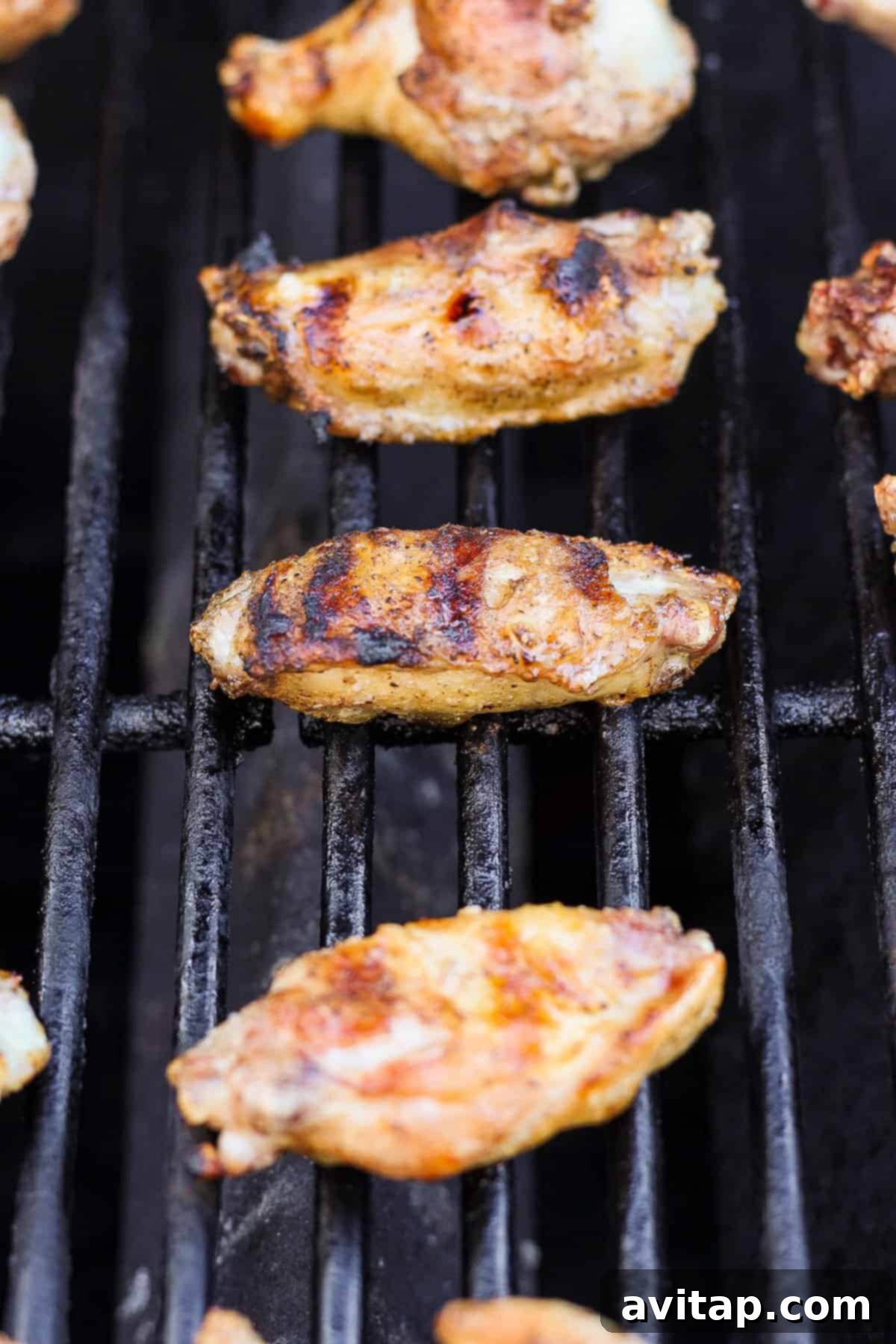 Grilled chicken wings on a barbecue grill with grill marks visible.
