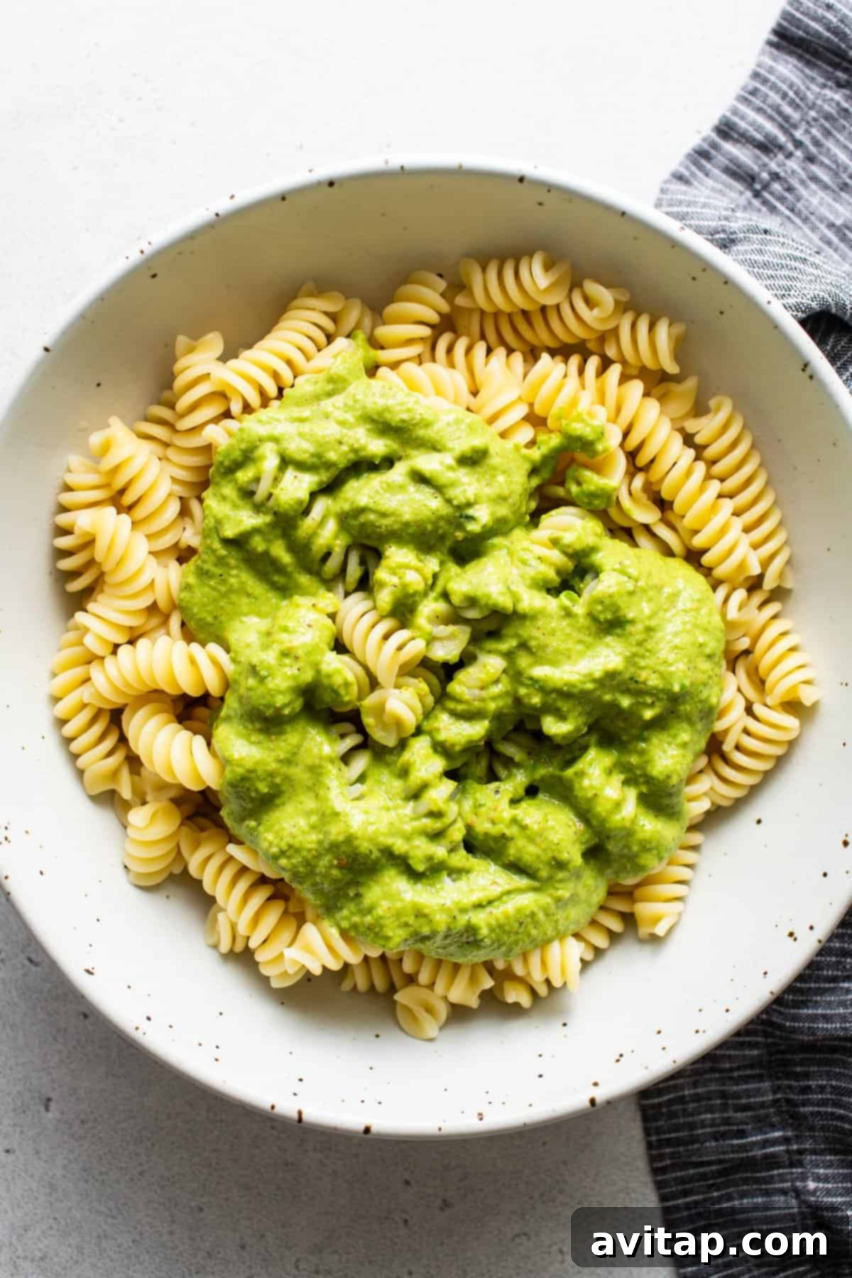 Fresh Sweet Pea Pesto Pasta 4 A bowl of rotini pasta generously coated with creamy green avocado sauce, suggesting a rich, plant-based texture for pesto.