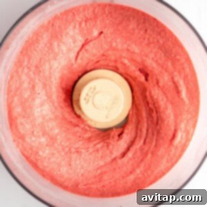 Top view of a food processor containing freshly blended strawberry puree, now smooth and ready for the next step.