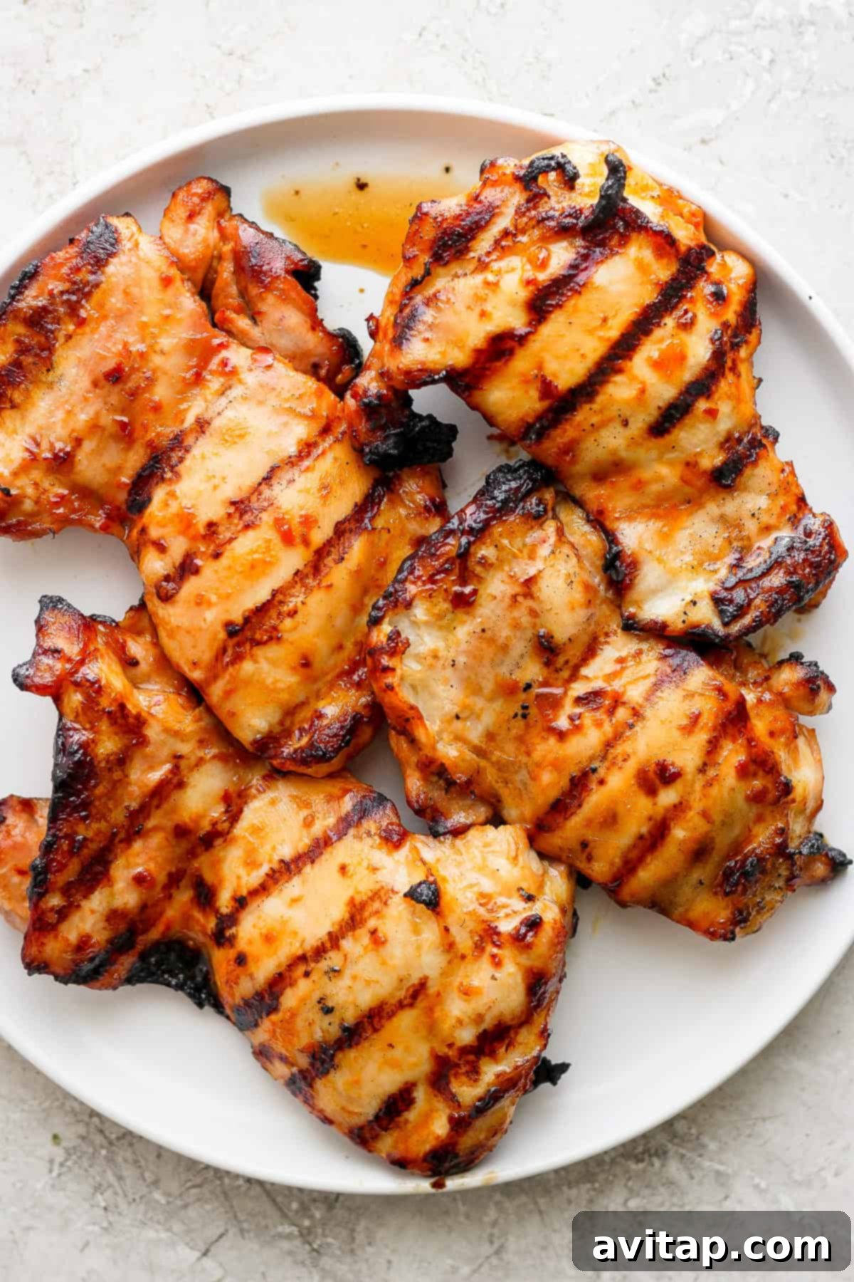 Tropical Grilled Coconut Chicken 4 Grilled chicken thighs in a pan, topped with bell peppers, onions, and fresh herbs.
