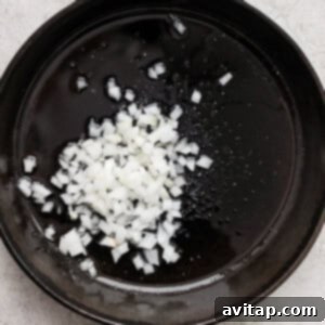 A frying pan with onions sautéing in olive oil.