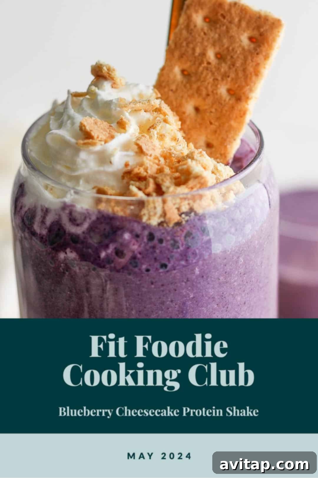 A vibrant purple blueberry cheesecake protein smoothie in a tall glass, garnished with fresh blueberries and a mint leaf.