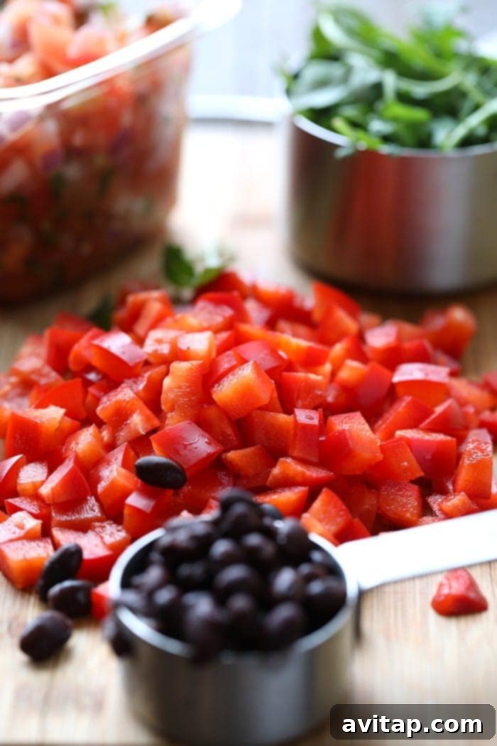 Close-up of freshly diced red peppers and a measuring cup brimming with black beans, ready for a delicious omelette.
