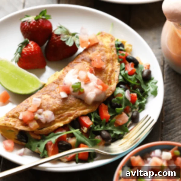 A plate of omelet with black beans, strawberries and salsa.