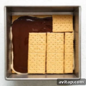 A baking dish with a layer of chocolate topped by aligned graham crackers, preparing for a s'mores dessert.