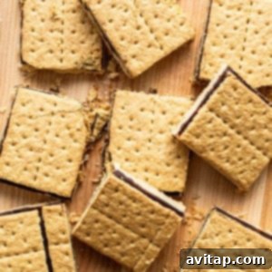 Smores bars with a gooey chocolate filling, scattered on a wooden surface.