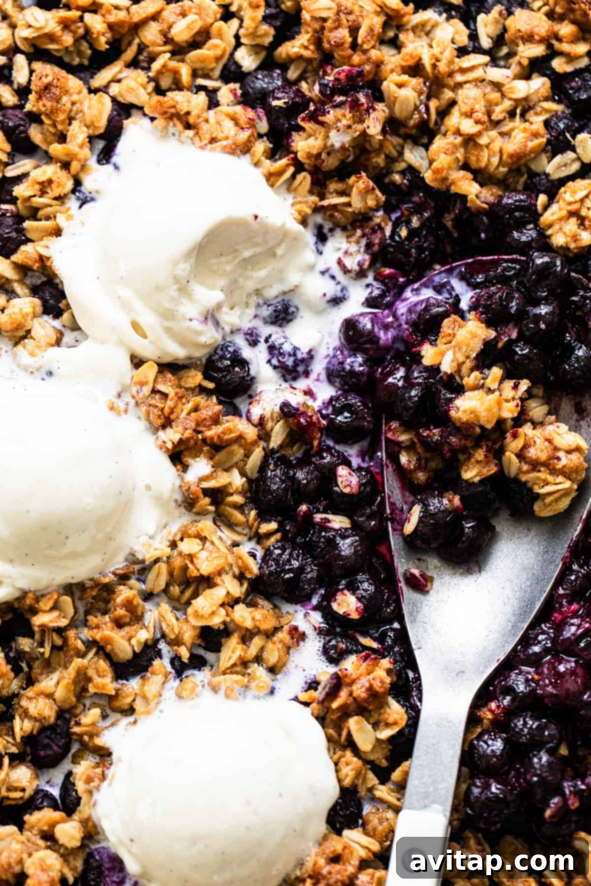 Baked blueberry crumble with scoops of vanilla ice cream, presented beautifully on a sheet pan.