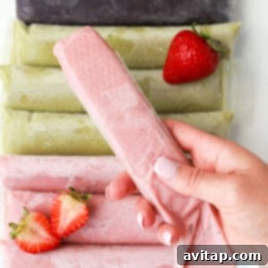 A person holding a strawberry ice cream in front of a pile of strawberries.