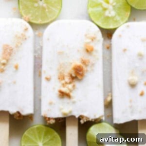 Close-up of a Coconut Key Lime Pie Popsicle with a bite taken out, showing the creamy texture and crust.