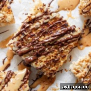 Close-up of toasted rice Krispie treats dessert bars topped with caramel and chocolate drizzle on a parchment paper background, showcasing their irresistible toppings.