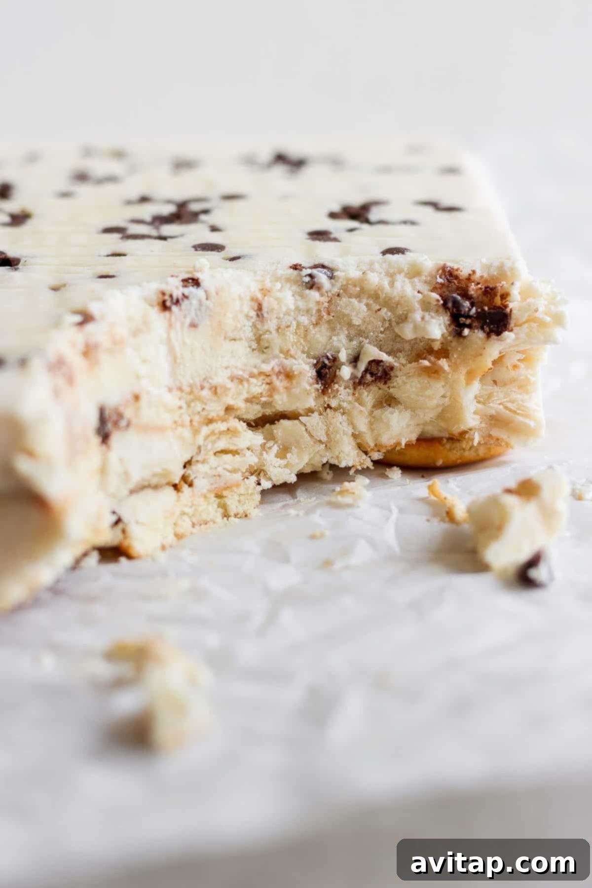 Peanut Butter Banana Icebox Delight 5 A partially eaten ice cream cake with chocolate chips and a hint of peanut butter banana lies on white parchment paper.