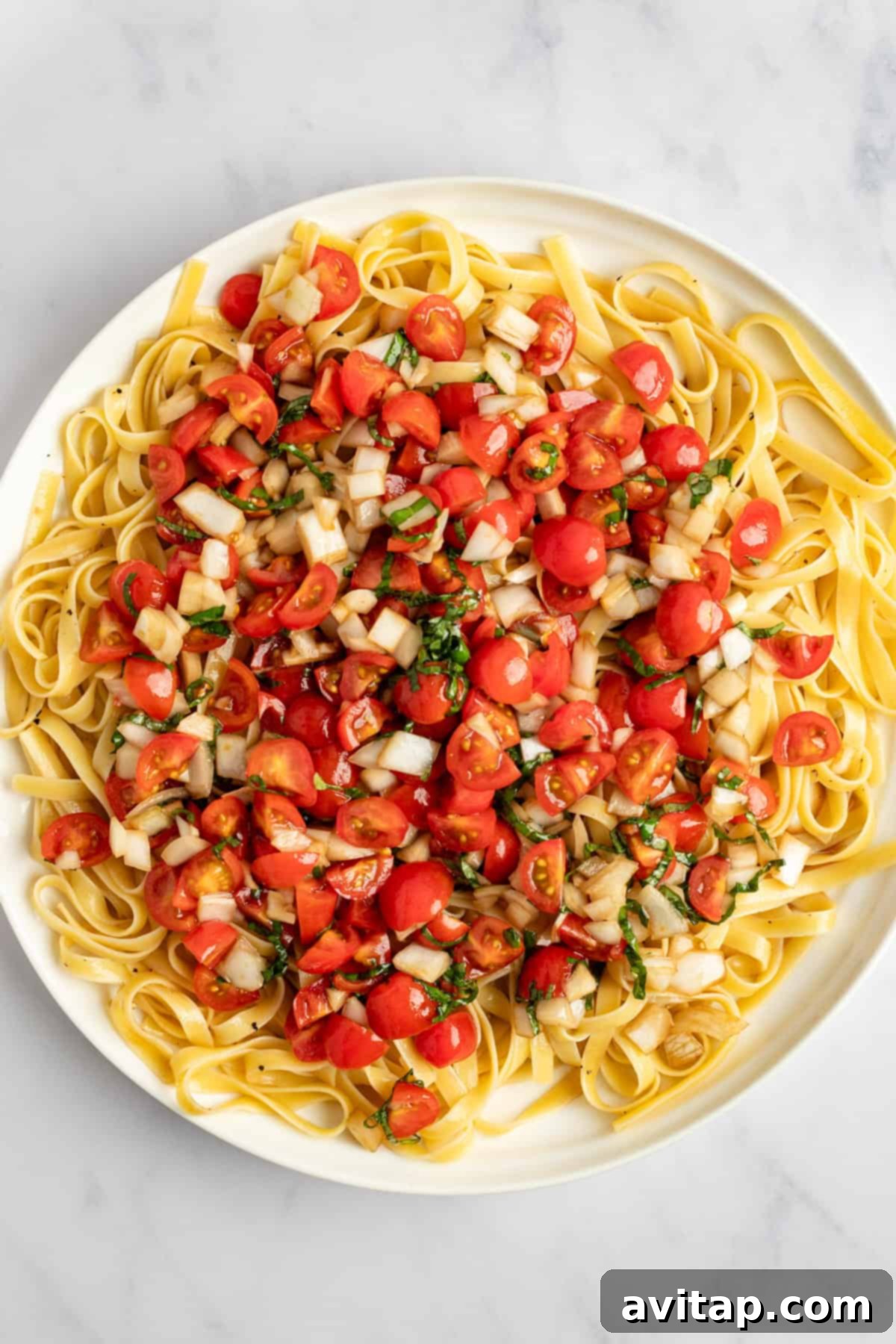 A serving of perfectly cooked fettuccine pasta, ready for the fresh bruschetta topping and creamy burrata.