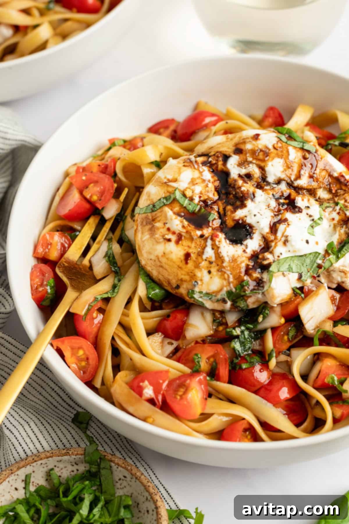 A bowl of fettuccine pasta topped with grilled chicken, cherry tomatoes, and basil, suggesting serving options for the bruschetta pasta.