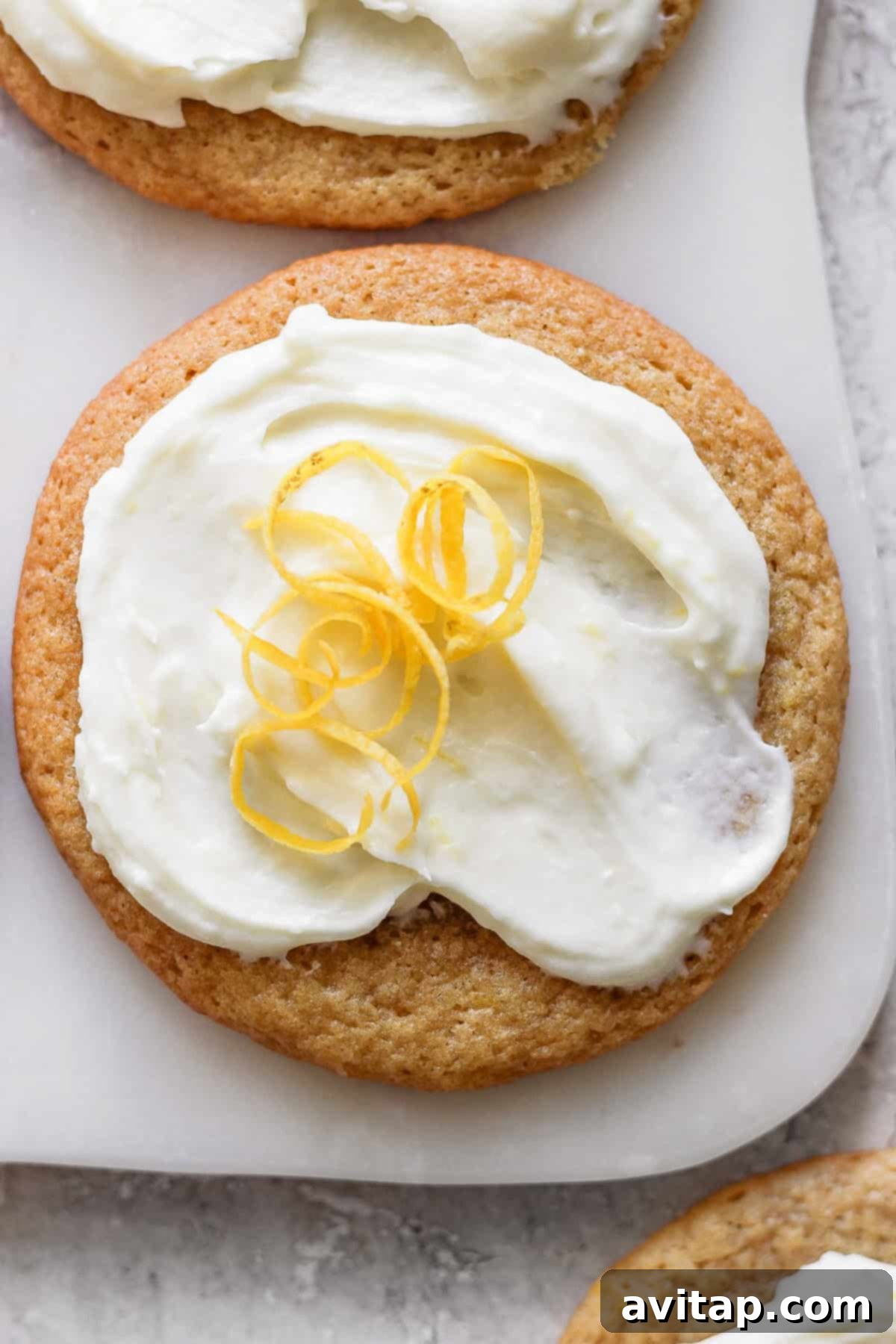 Sunshine Lemon Cream Cheese Cookies 5 A lemon cookie adorned with cream cheese frosting and garnished with a twist of lemon peel, showcasing its perfect bake and delightful decoration.