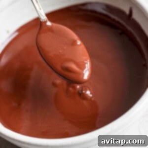 Delicious Homemade Dilly Bars 9 A spoon is held above a bowl of melted chocolate.