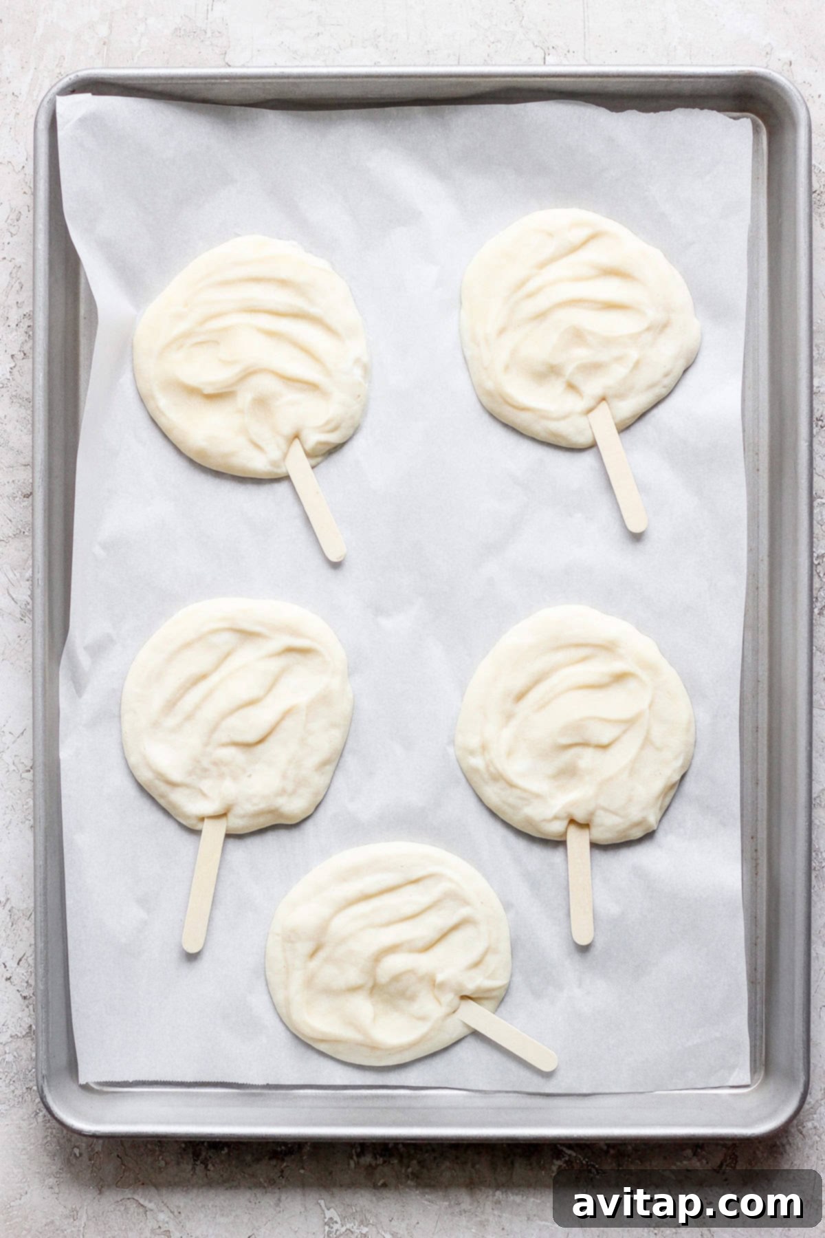 Delicious Homemade Dilly Bars 3 Four raw popsicle-shaped dough pieces on parchment paper in a gray baking tray.