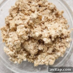 A glass bowl containing a mixture of oats and flour sits on a grey countertop.