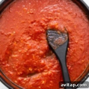 Rich tomato sauce simmering in a pan, thickening to perfection with aromatic spices and herbs.