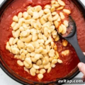 A skillet filled with the rich, bubbling mixture of butter beans and tomato sauce, creating a harmonious blend of flavors.