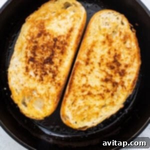 Thick-cut bread slices toasting in a cast iron skillet to a perfect golden crisp, forming the ideal base.