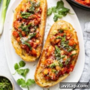 Two slices of hearty toast topped with the delicious butter bean mixture, garnished with fresh herbs and Parmesan cheese, ready to be enjoyed.