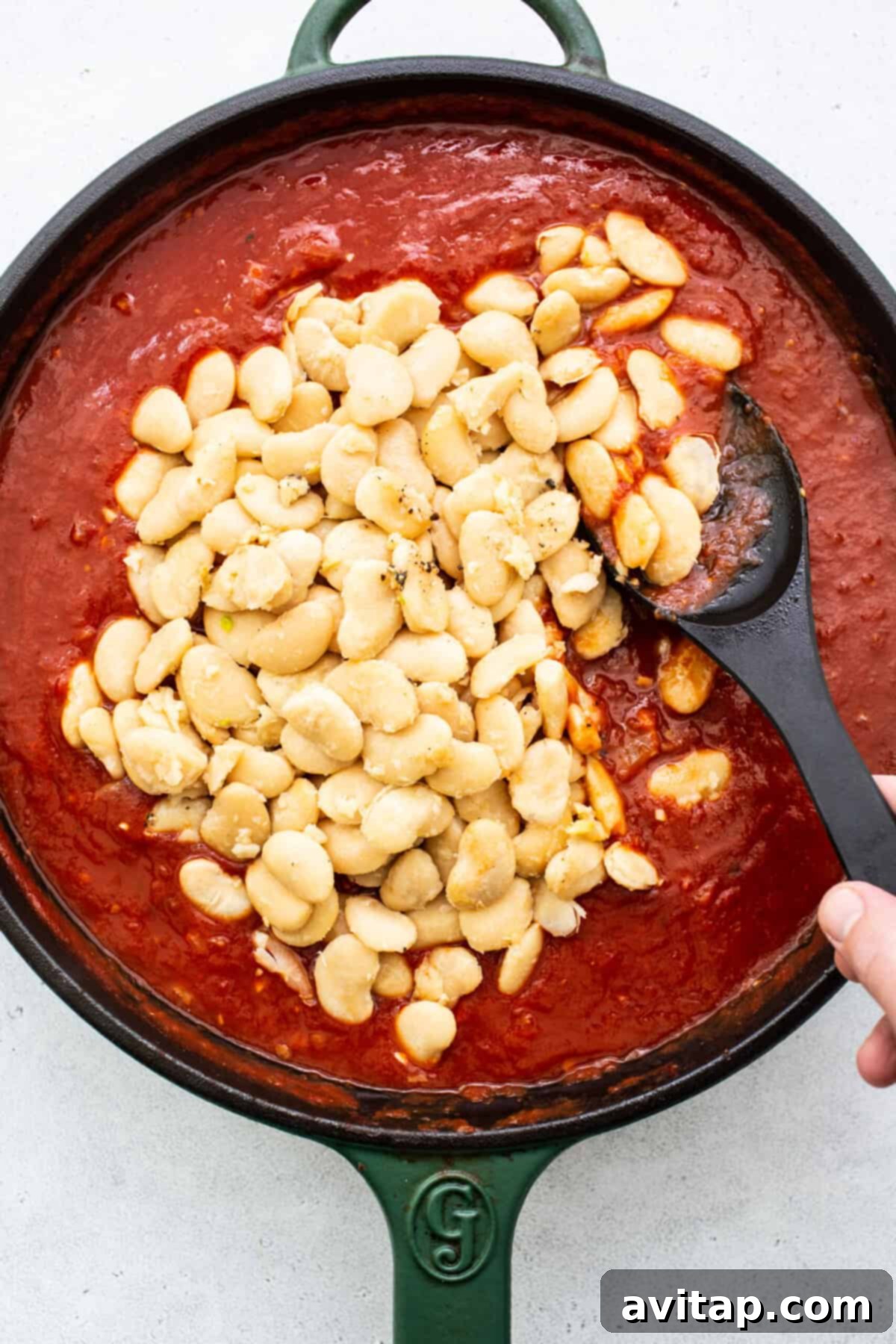A cast iron skillet brimming with the rich, simmering tomato and butter bean mixture, ready to be served over toasted bread.