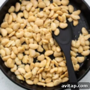White beans gently sautéing in a frying pan, ready to be infused with flavor.